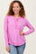 woman wearing a pink long sleeve henley top with button details and a curved hem, smiling at the camera