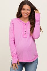 woman wearing a pink long sleeve maternity top with button details and a visible baby bump