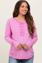 woman wearing a pink long sleeve maternity top with button details and ribbed cuffs, smiling at the camera