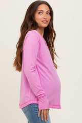 woman wearing a bright pink long sleeve maternity top with a visible baby bump and casual jeans
