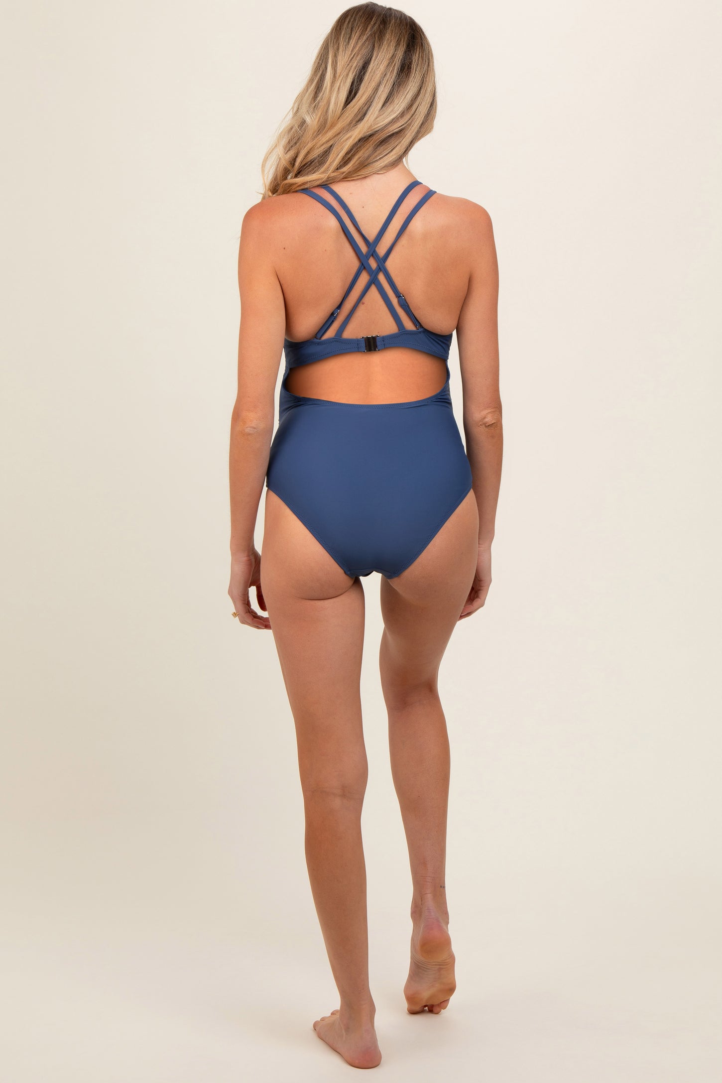 woman wearing a navy blue maternity swimsuit with crisscross straps at the back