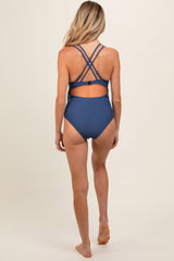 woman wearing a navy blue maternity swimsuit with crisscross straps at the back