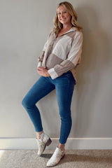 woman wearing a striped maternity blouse and blue skinny jeans, gently cradling her baby bump