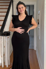 woman wearing a black ribbed maternity dress with ruffle sleeves and holding her baby bump