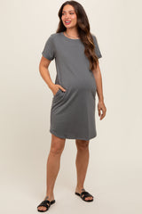 woman wearing a gray short sleeve maternity dress with pockets and showing her baby bump