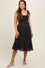 woman wearing a black floral print maternity dress with smocked bodice and tie shoulder straps