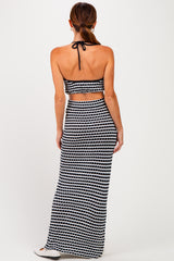 woman wearing a black and white patterned two-piece maxi dress with a halter top and open back