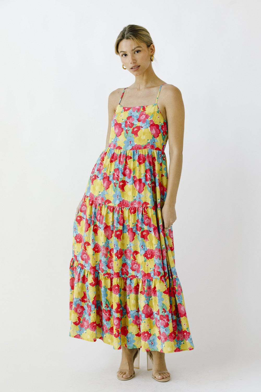 woman wearing a colorful floral maxi dress with a tiered design and adjustable spaghetti straps