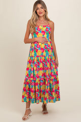 woman wearing a colorful floral maternity maxi dress with a tiered skirt and holding her baby bump
