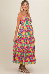 woman wearing a colorful floral maternity maxi dress with a fitted bodice and tiered skirt, showcasing her baby bump