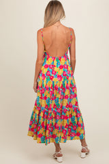 woman wearing a colorful floral maternity maxi dress with a low back and tiered skirt