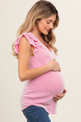woman wearing a pink and white striped maternity top with ruffle sleeves and holding her baby bump