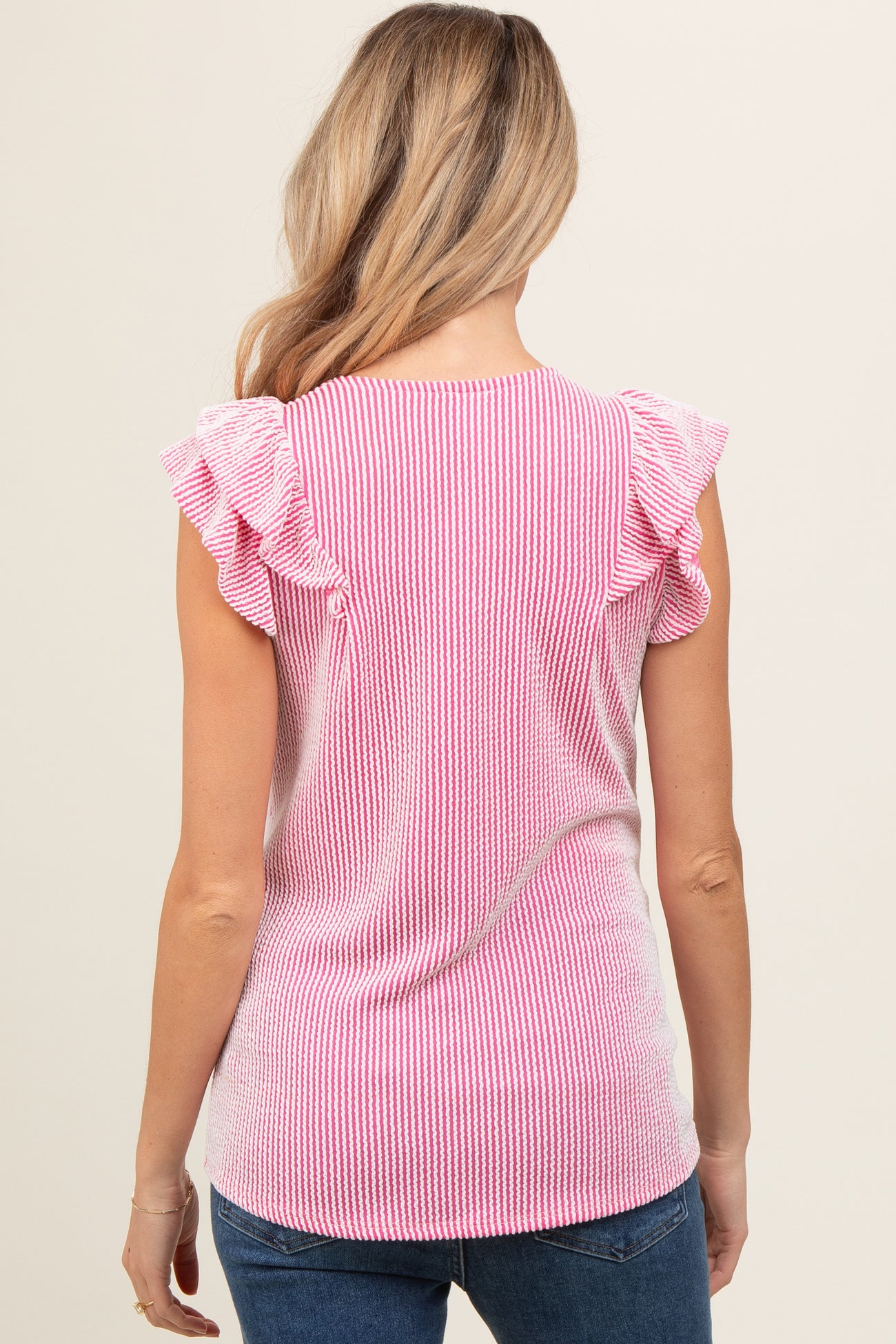 woman wearing a pink and white striped maternity top with ruffled sleeves from the back