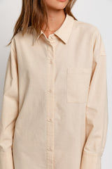 woman wearing a beige long sleeve button-up shirt with a chest pocket