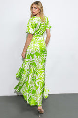 woman wearing a green floral maxi dress with puff sleeves and a ruffled hem, seen from the back