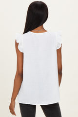 back view of a woman wearing a white sleeveless top with ruffle sleeves and a subtle dotted pattern