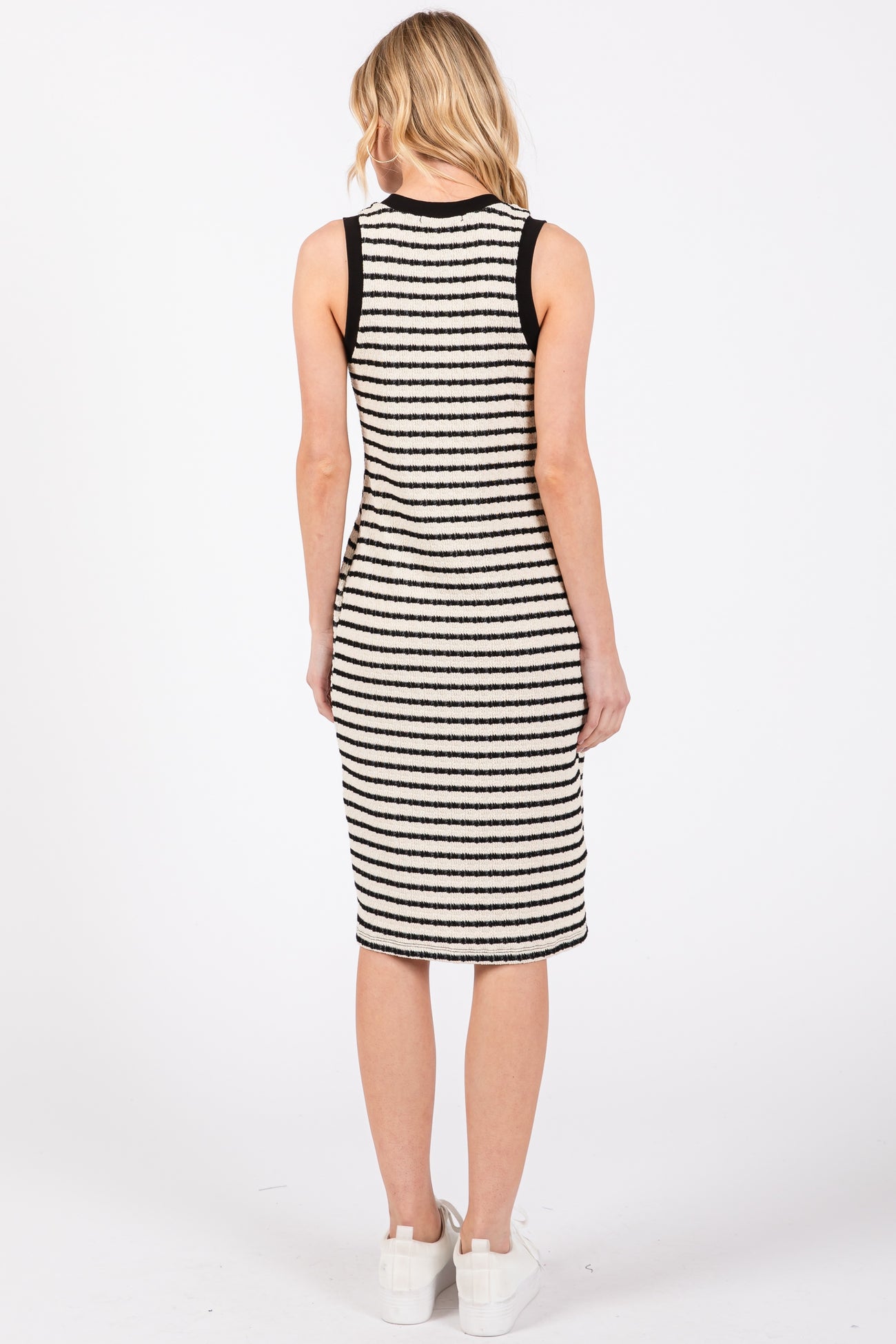 woman wearing a black and white striped sleeveless midi dress, view from the back