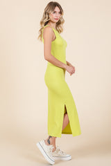 woman wearing a bright yellow sleeveless maxi dress with a side slit and paired with white sneakers