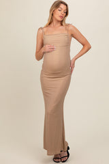 woman wearing a gold maternity maxi dress with spaghetti straps and a baby bump
