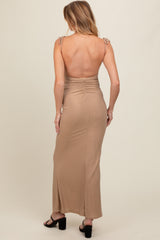 woman wearing a backless tan maternity maxi dress with tie straps and ruching detail