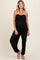 woman wearing a black strapless maternity jumpsuit with ruched detailing and side pockets, showcasing her baby bump
