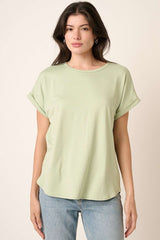 woman wearing a light green short sleeve top with rolled sleeves and relaxed fit, paired with light blue jeans