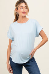 woman wearing a light blue maternity top with rolled sleeves and a visible baby bump