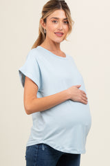 woman wearing a light blue short sleeve maternity top and holding her baby bump
