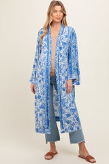 woman wearing a blue floral maternity kimono over a tan top and jeans
