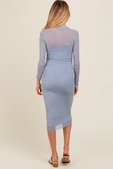 woman wearing a light blue long sleeve maternity dress with a fitted silhouette and sheer detail on the back