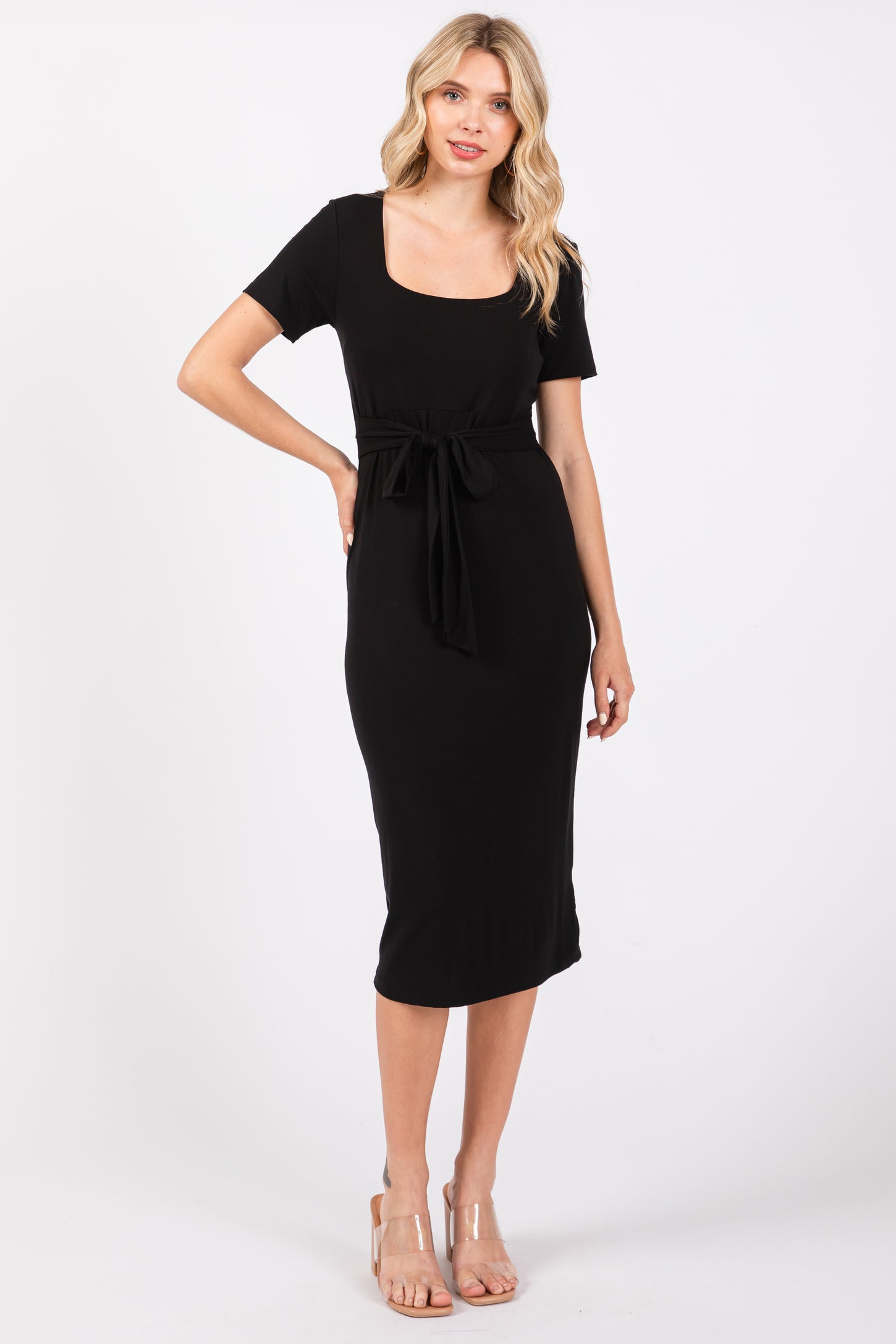 woman wearing a black midi dress with a square neckline and a tie waist detail