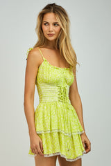woman wearing a light green floral mini dress with adjustable straps and a tiered skirt