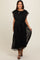woman wearing a black maternity dress with short flutter sleeves and a tied waist detail, posing with a smile