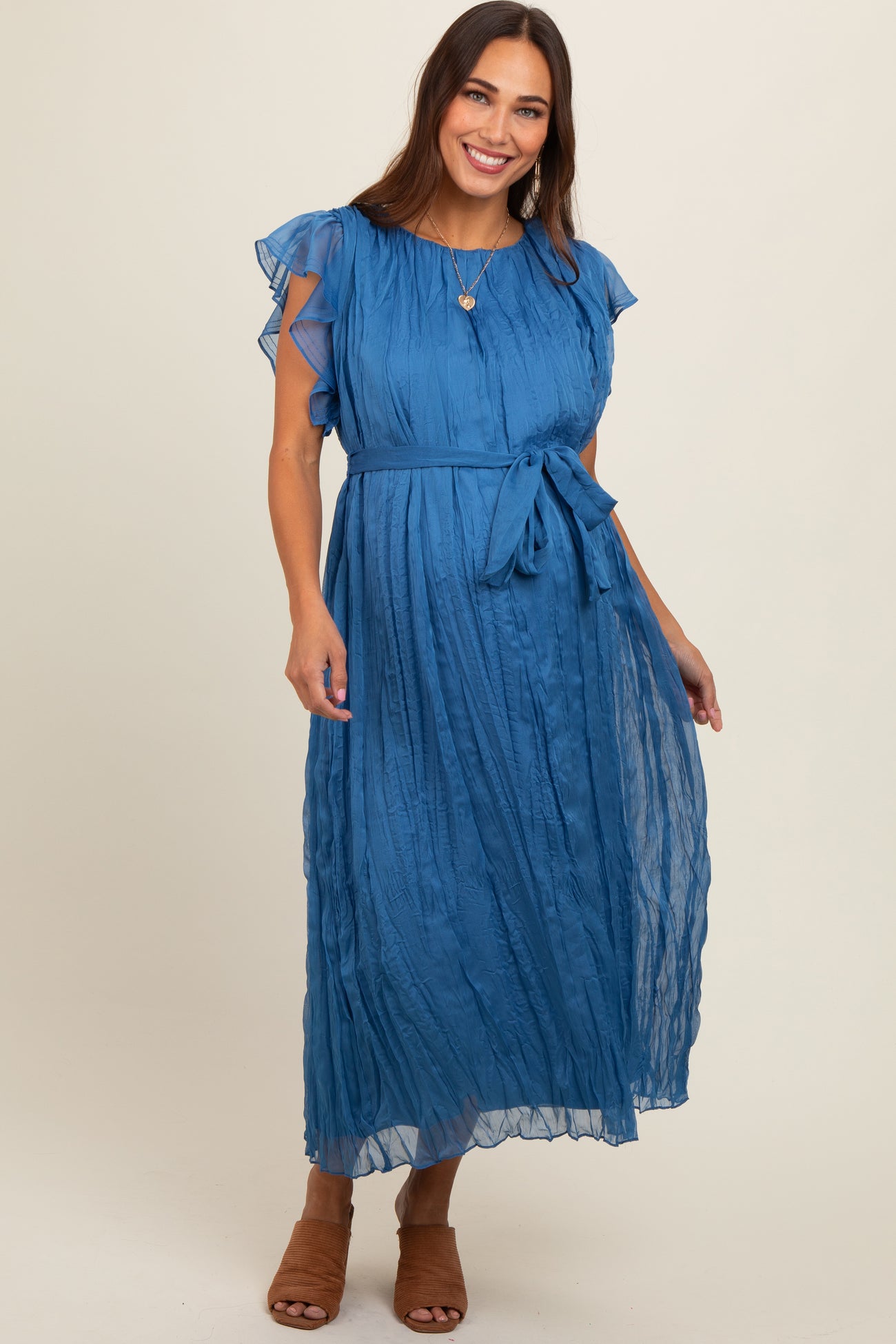 woman wearing a blue maternity maxi dress with flutter sleeves and a tie waist detail