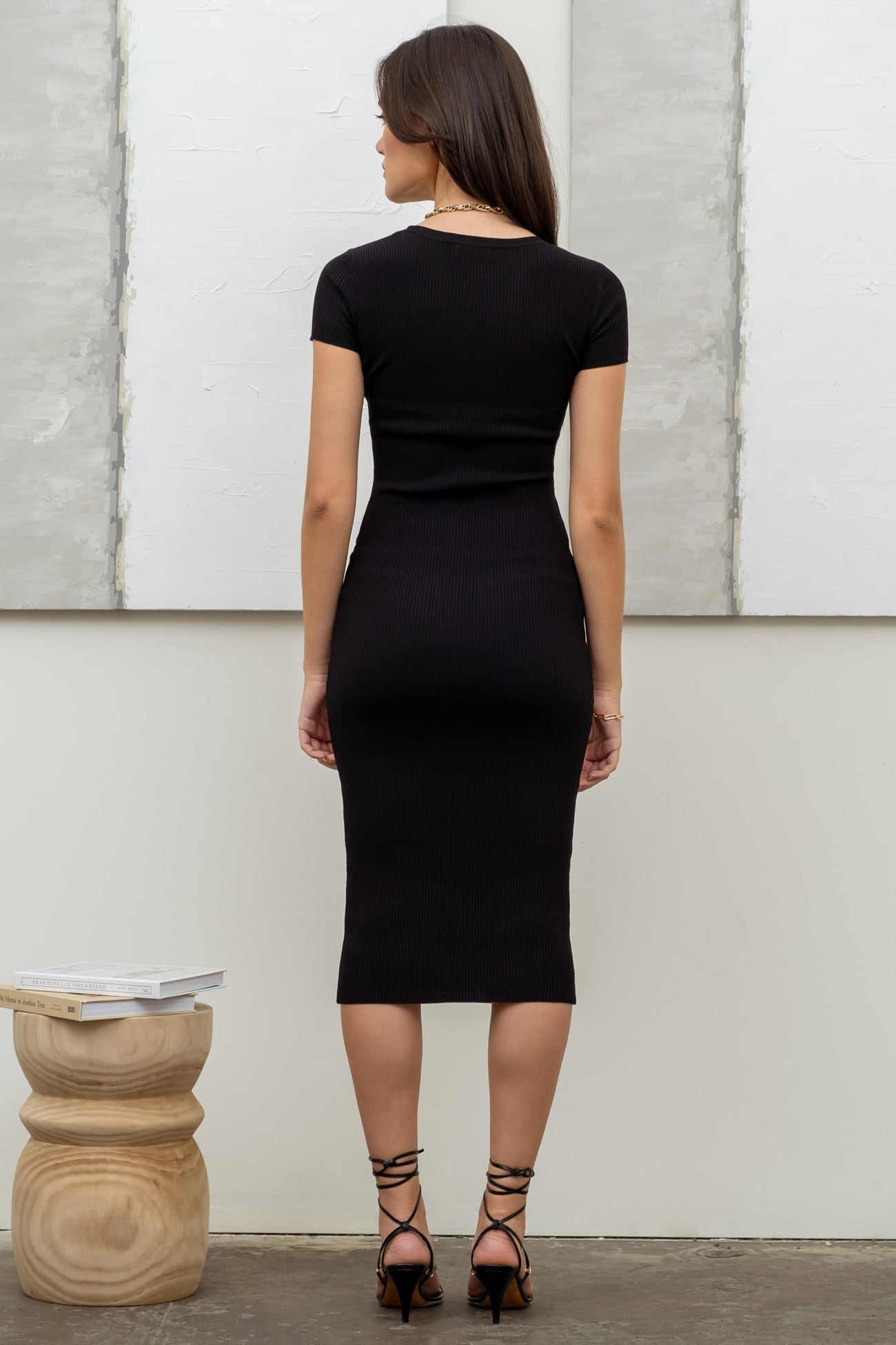 woman wearing a black ribbed midi dress with short sleeves and a fitted silhouette