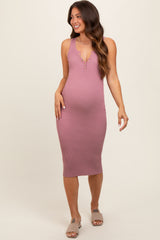 woman wearing a pink ribbed sleeveless maternity dress with a deep V-neck and button details, showing a baby bump
