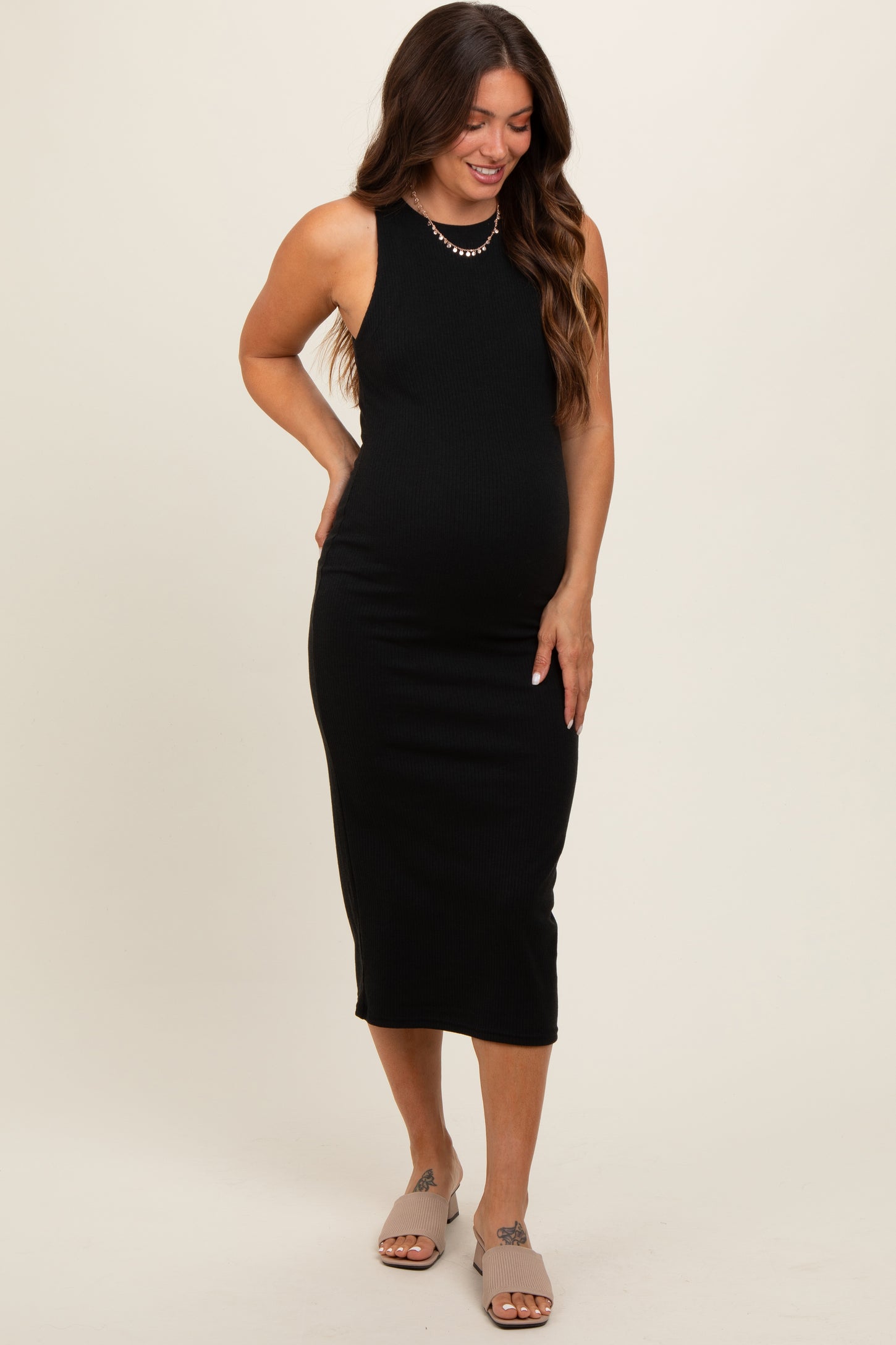 woman wearing a black ribbed maternity midi dress and showcasing her baby bump