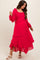woman wearing a bright pink maternity dress with ruffle details and long sleeves, showcasing her baby bump