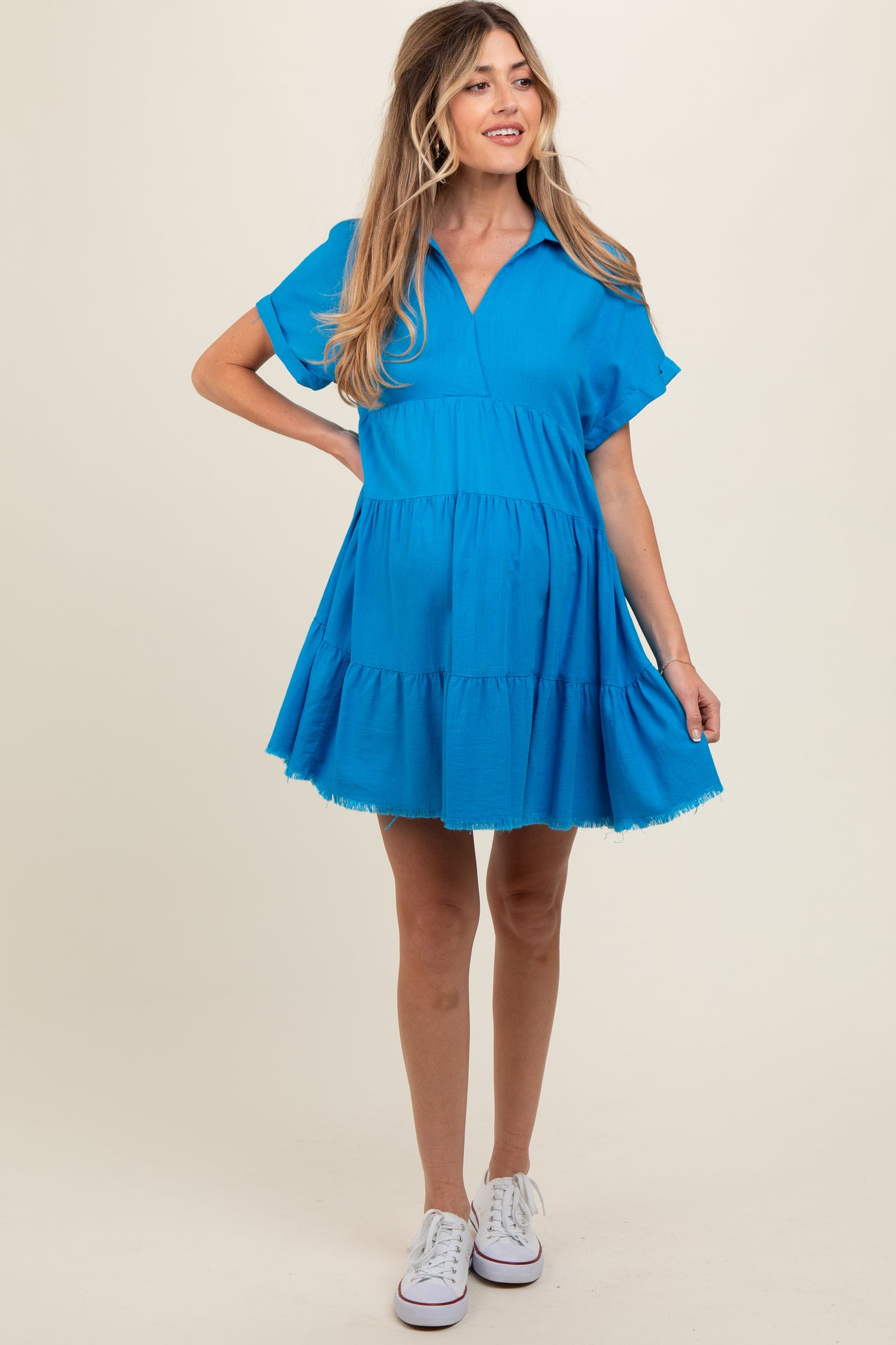 woman wearing a bright blue short sleeve maternity dress with a tiered skirt and a v-neckline