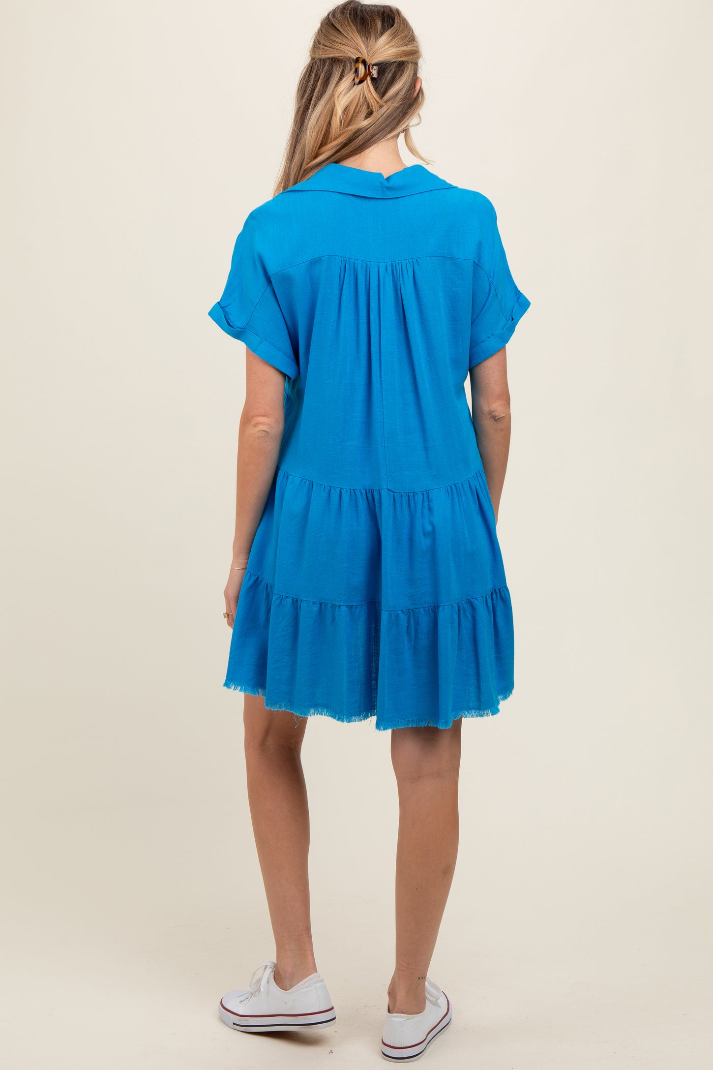 woman wearing a blue short sleeve maternity dress with a tiered skirt, showing the back view