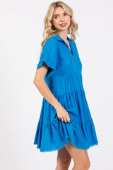 woman wearing a bright blue tiered short dress with a collar and short sleeves
