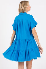 woman wearing a bright blue short sleeve tiered dress with a fringe hem and a relaxed fit