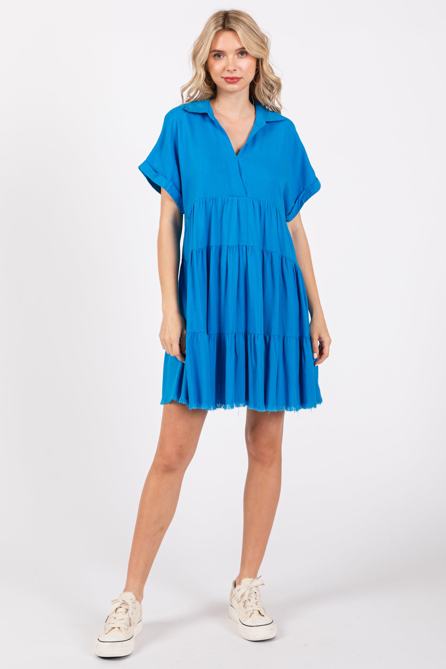 woman wearing a bright blue short sleeve tiered dress with a relaxed fit and v-neckline
