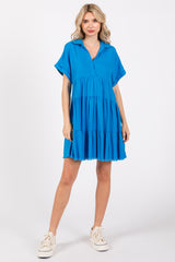 woman wearing a bright blue short sleeve tiered dress with a relaxed fit and v-neckline