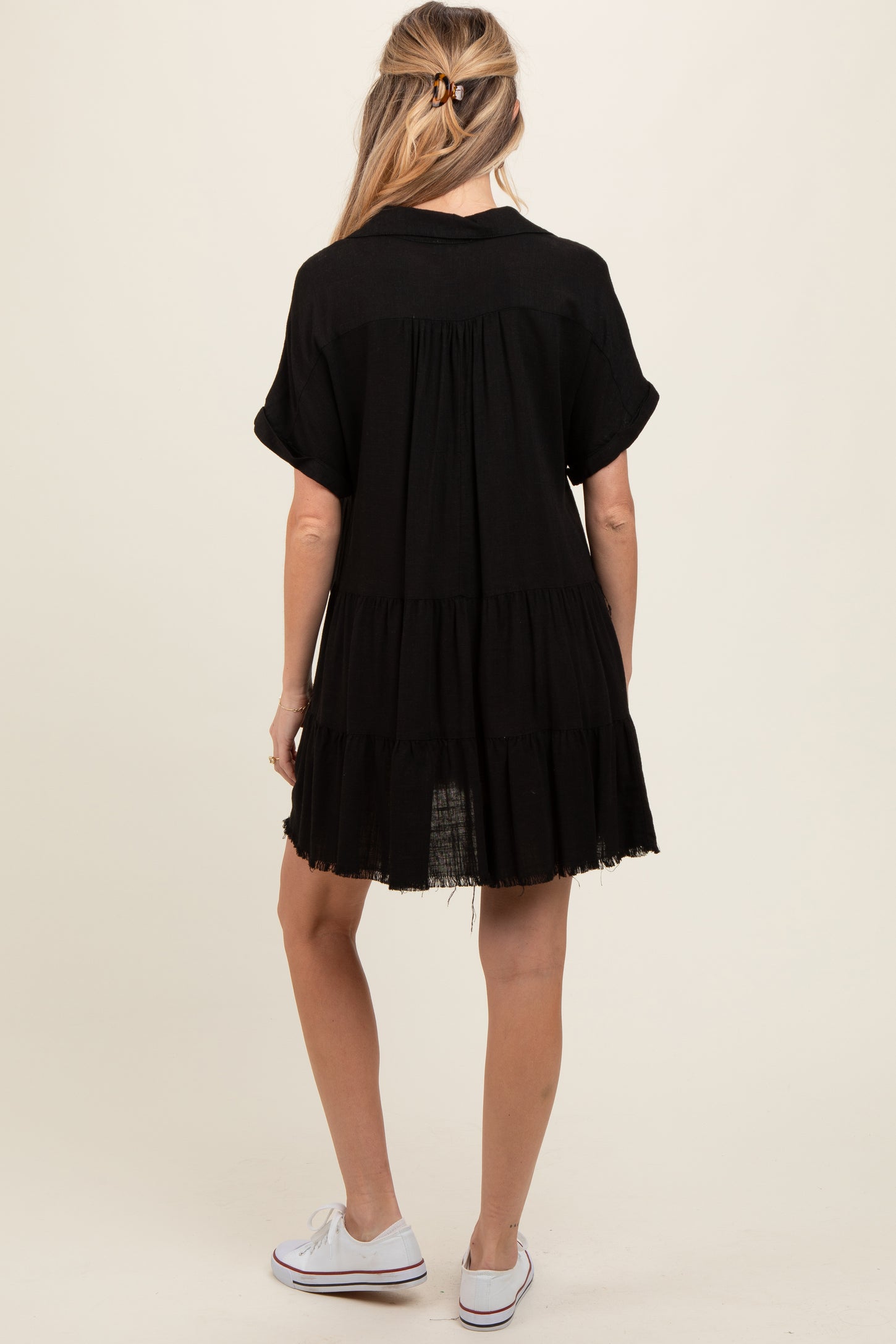 woman wearing a black short sleeve maternity dress with tiered ruffles, showing a casual and comfortable style from the back