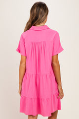 woman wearing a bright pink short sleeve maternity dress with tiered detailing and a collar, showing no visible baby bump