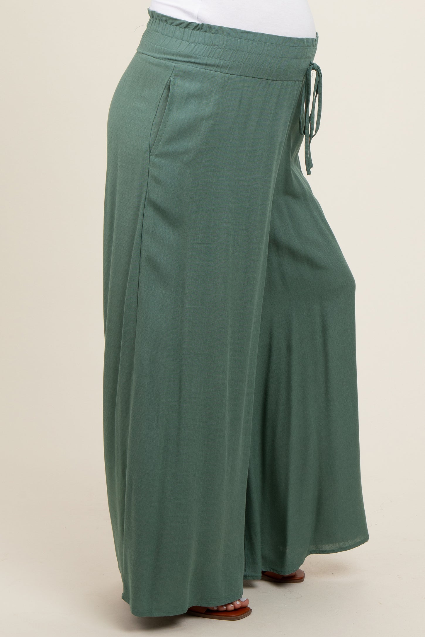 maternity wear in a soft green color, featuring wide-leg style and an elastic waistband, model shows a visible baby bump
