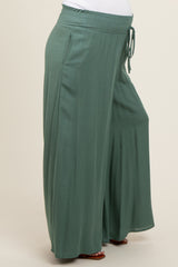 maternity wear in a soft green color, featuring wide-leg style and an elastic waistband, model shows a visible baby bump