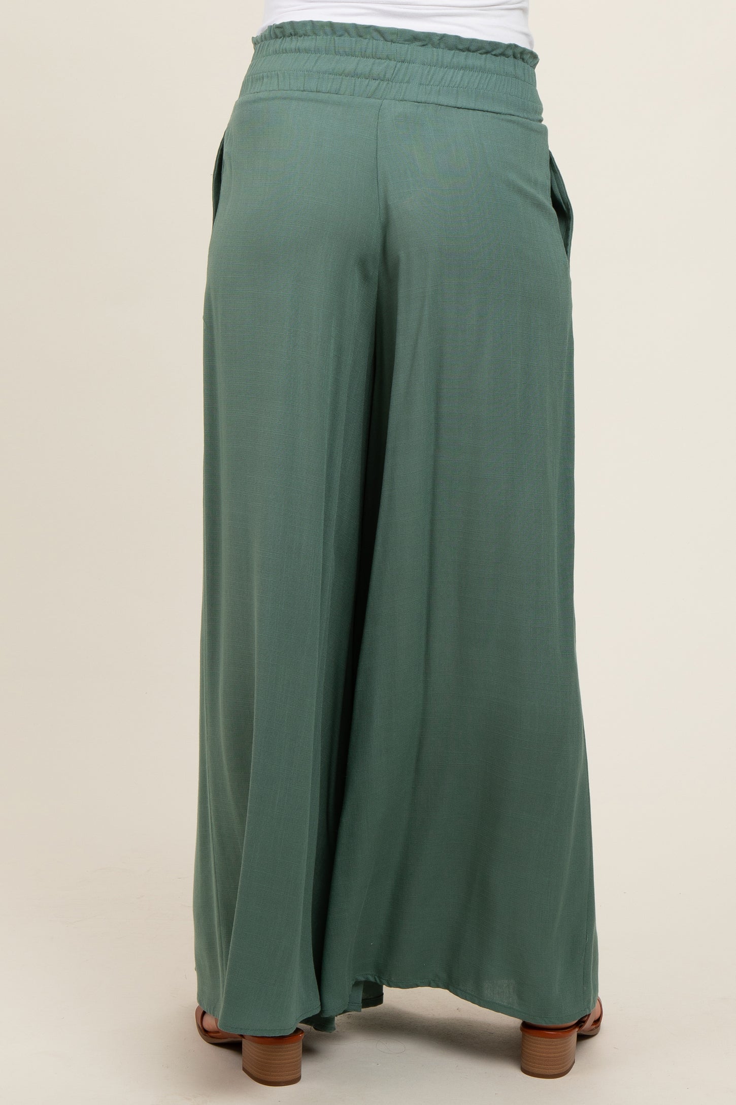 woman wearing green wide-leg maternity pants, showing the back with an elastic waistband and side pockets