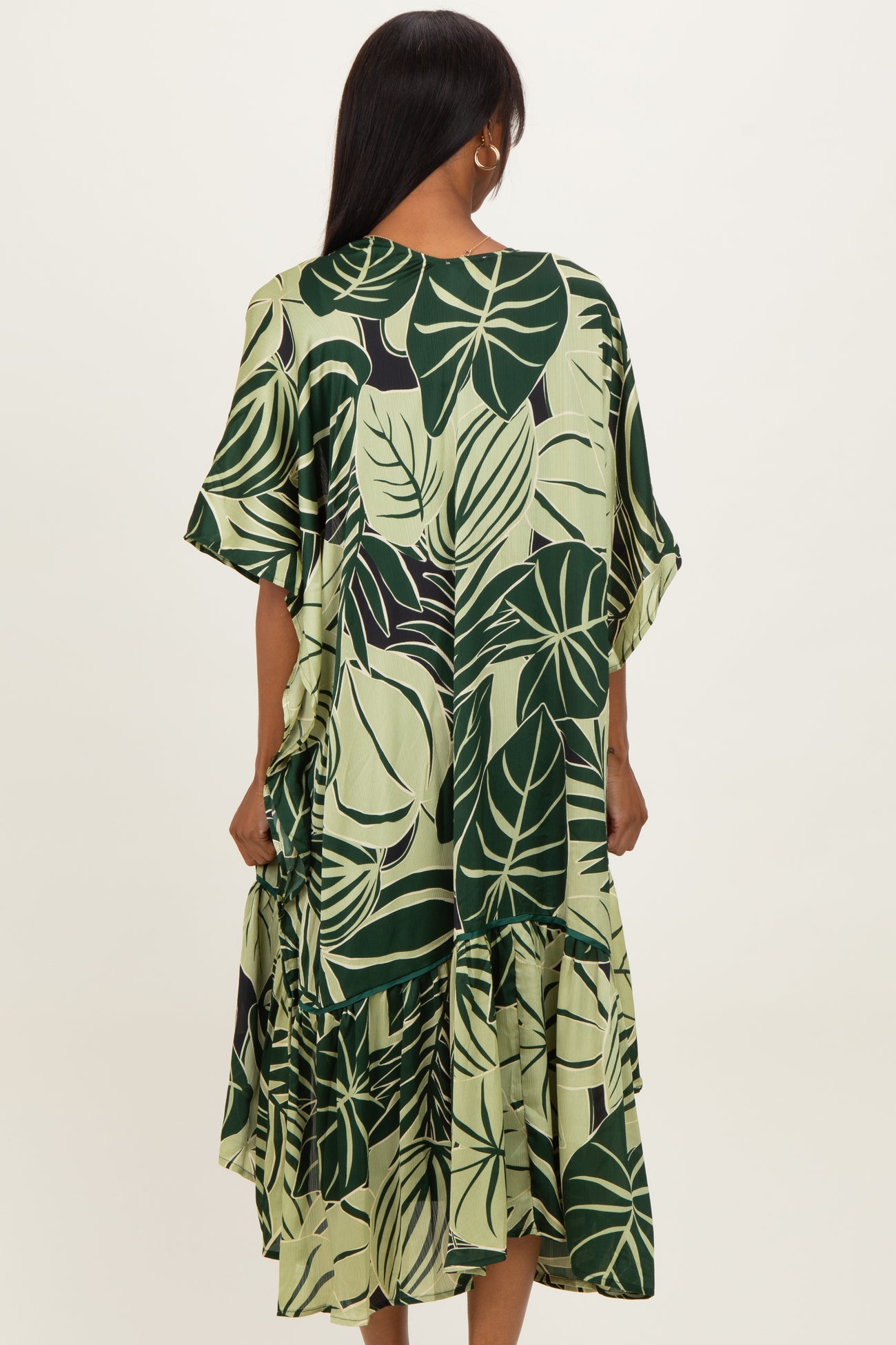 woman wearing a green tropical leaf print tiered dress with short sleeves from the back